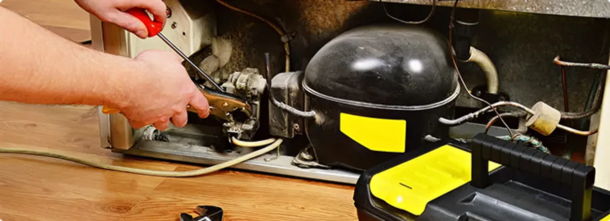 Refrigerator repair technician fixing the compressor and wiring in Penrose, CO
