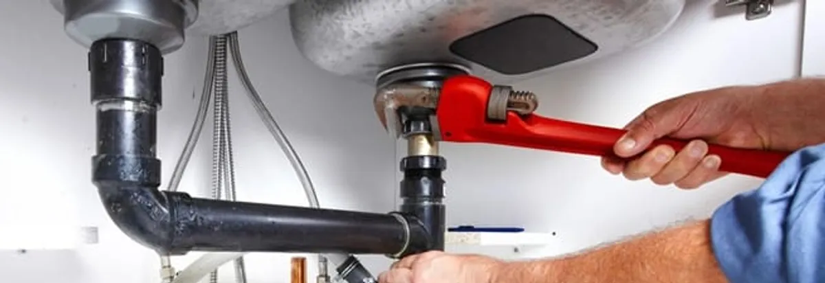 Garbage disposal repair technician tightening the sink drain and disposal connection in Colorado Springs, CO