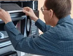 Appliance repair technician replacing a microwave vent filter in Colorado Springs, CO