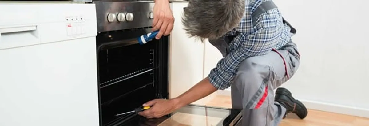 Oven repair technician inspecting and servicing an electric oven in Colorado Springs, CO