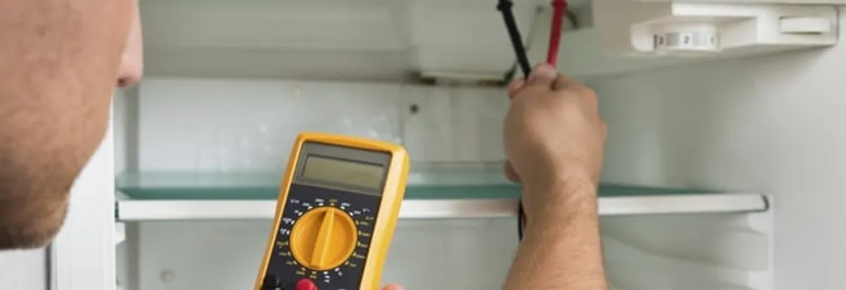 Refrigerator repair technician testing electrical components with a multimeter in Colorado Springs, CO