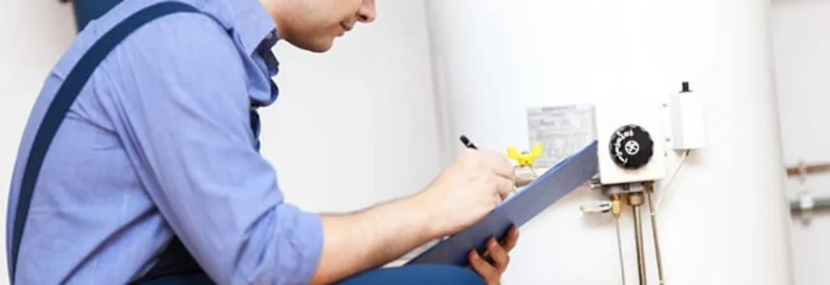 Water heater repair technician inspecting the unit and recording service notes in Colorado Springs, CO